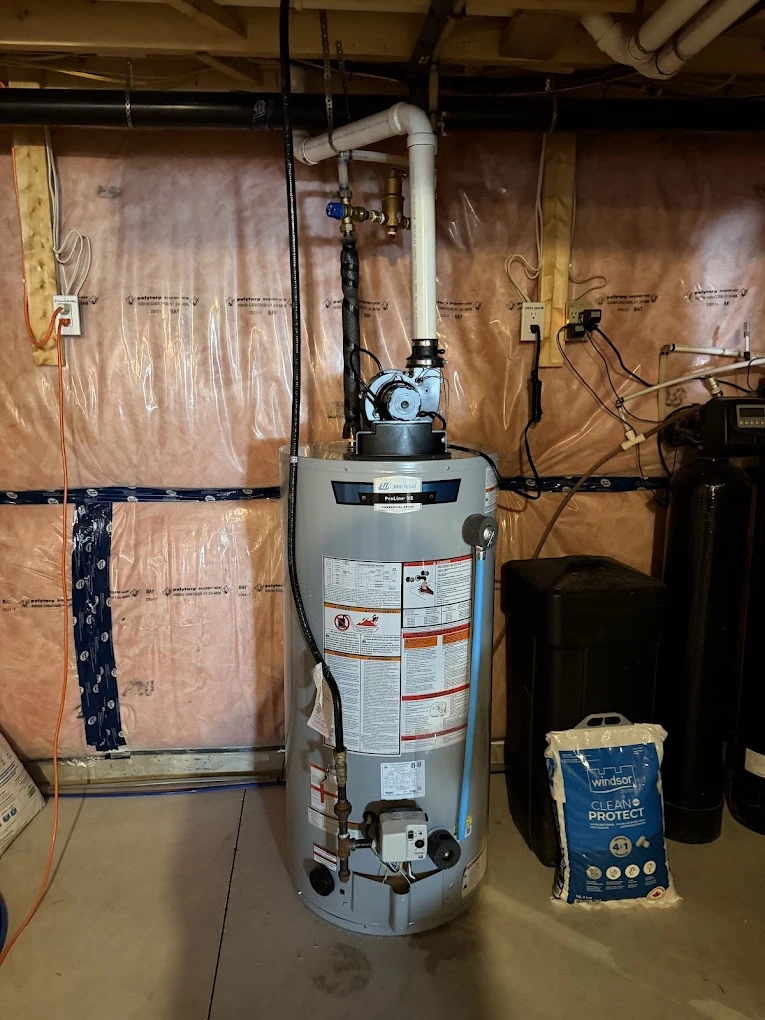 Gas water heater installed in a basement with power-vent piping running to the ceiling.