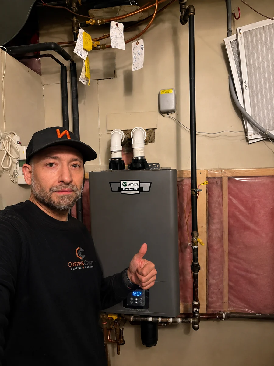 Joe, owner of CopperCraft Heating and Cooling, standing beside a newly installed tankless water heater.