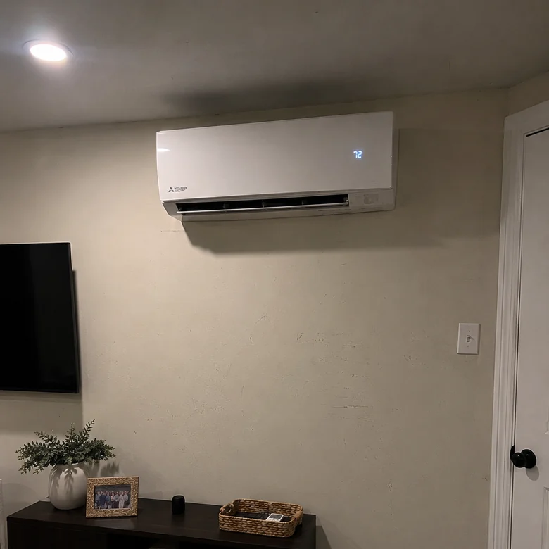 Wall-mounted Mitsubishi ductless mini-split head running at 72 degrees, high on a living-room wall.